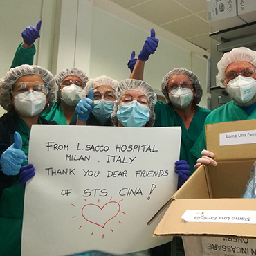 Group of hospital staff holding sign and box with masks