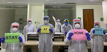 People in full protective gear holding papers saying 